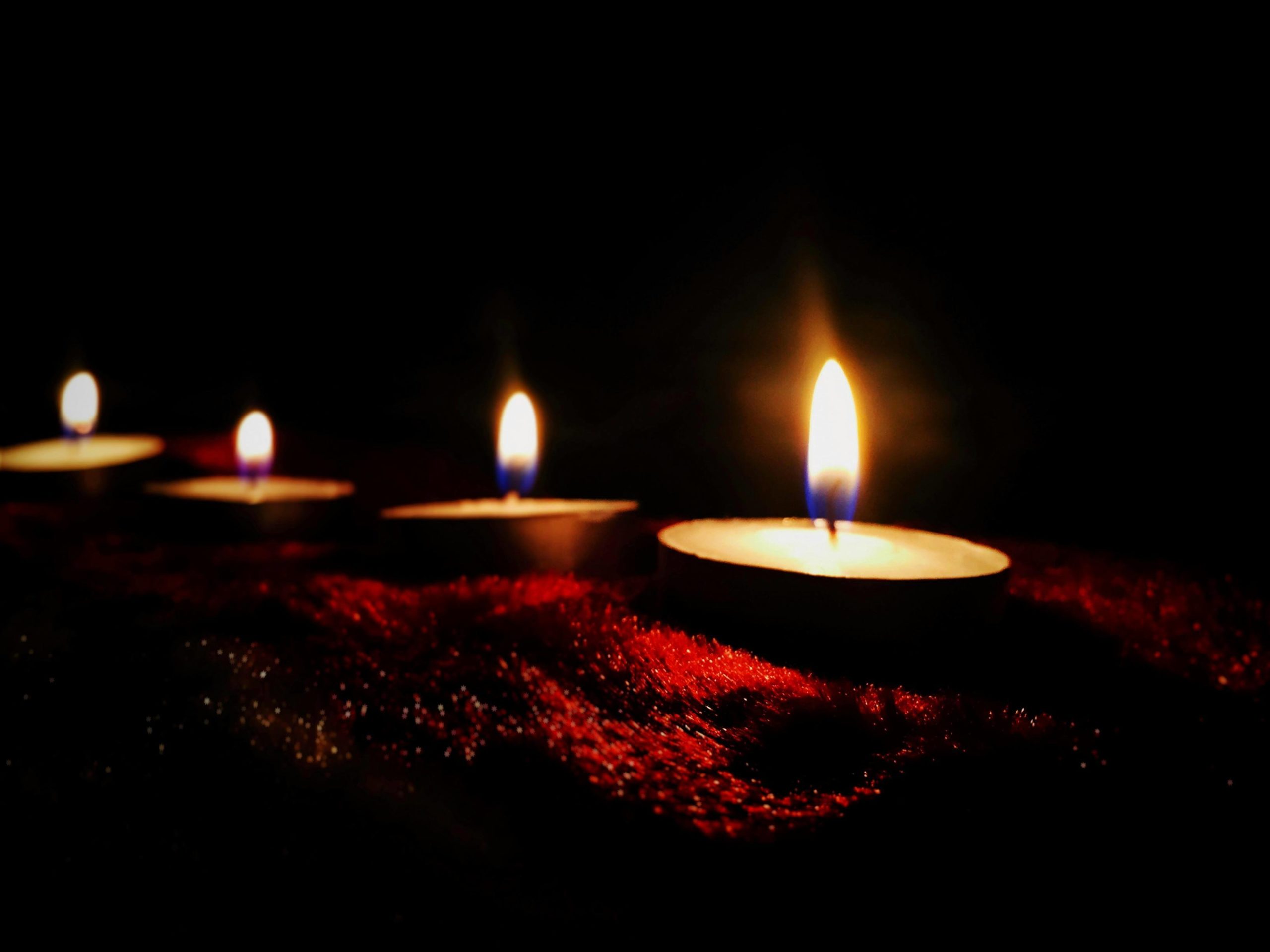 four candles on a red surface